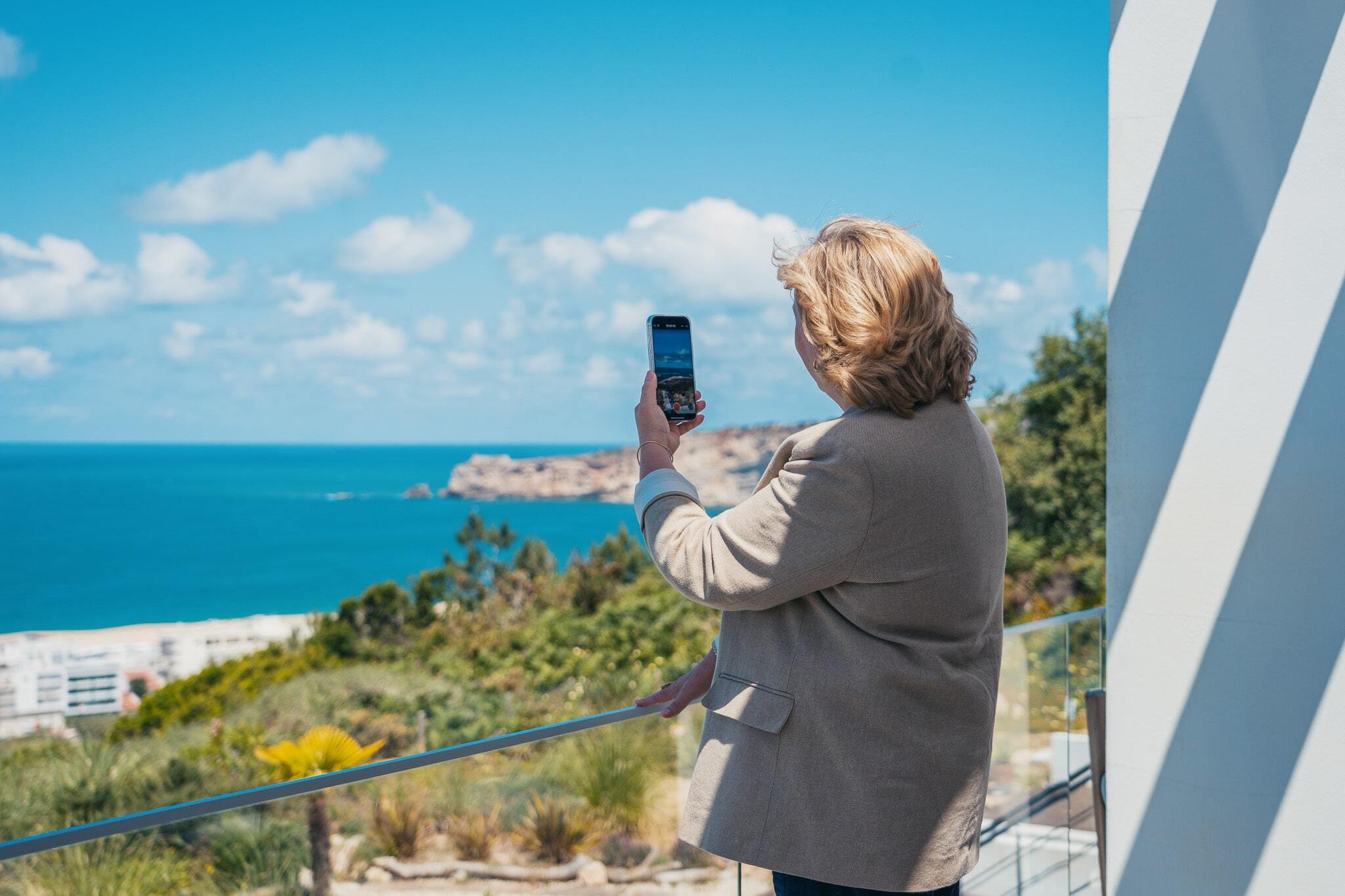 colleen standing on a balcony recording the portuguese coast line